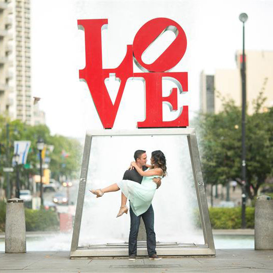 A bride in a grooms arm under the famous philadelphia love statue.