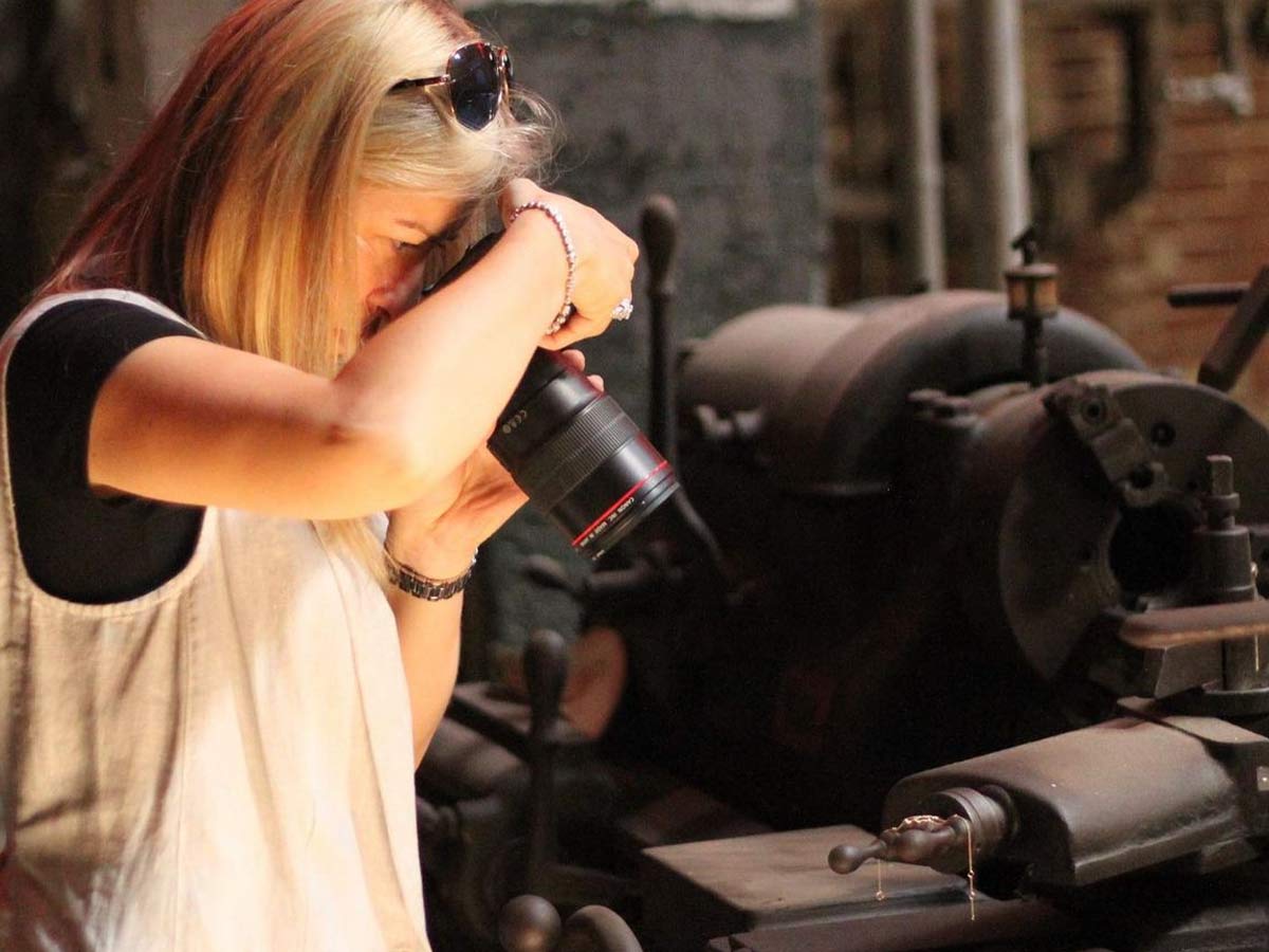 A woman holding a professional camera taking pictures of jewelry