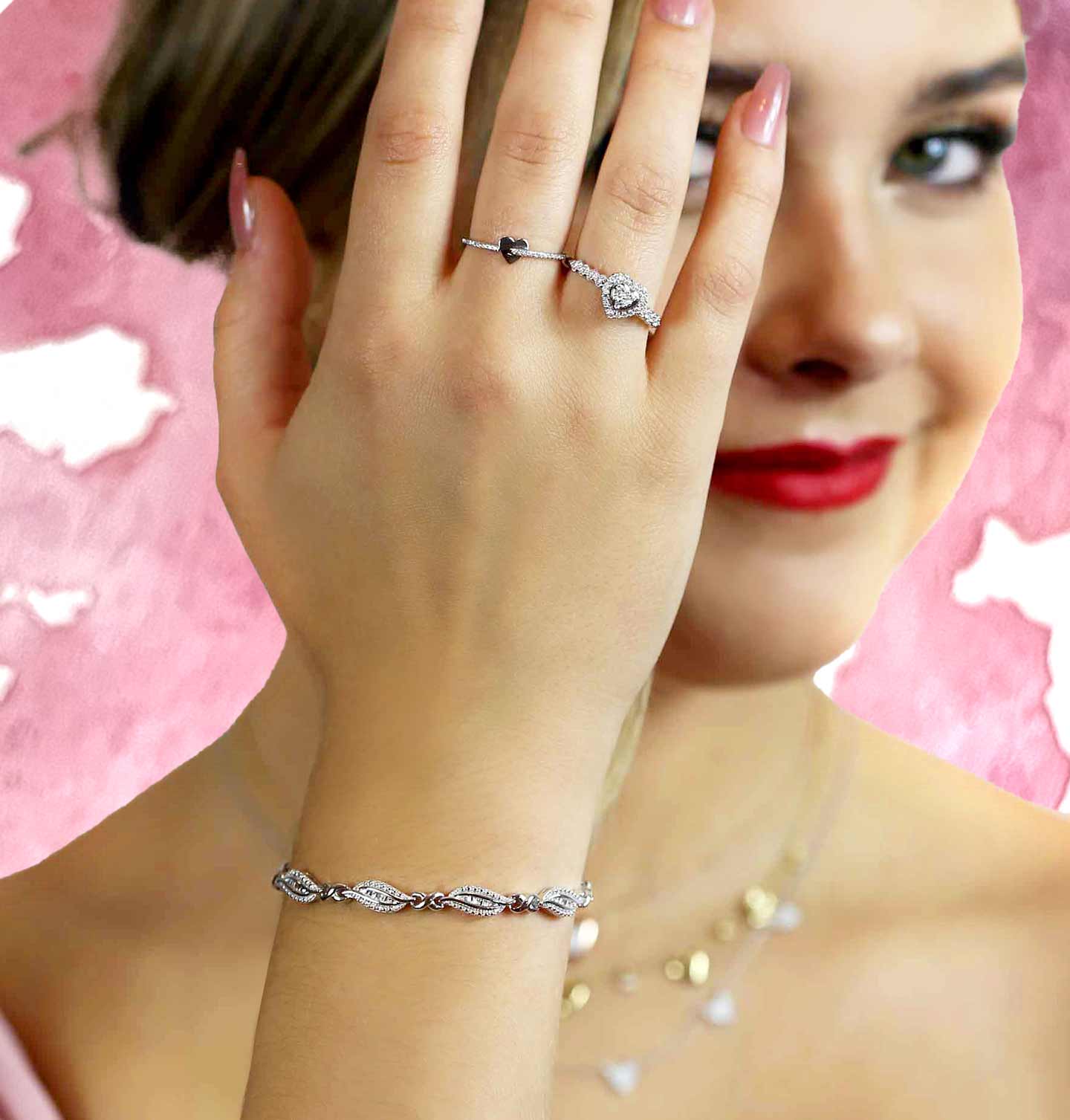 A girl holding up her hand to show off her stacked heart rings and our At Last Diamond Bracelet.