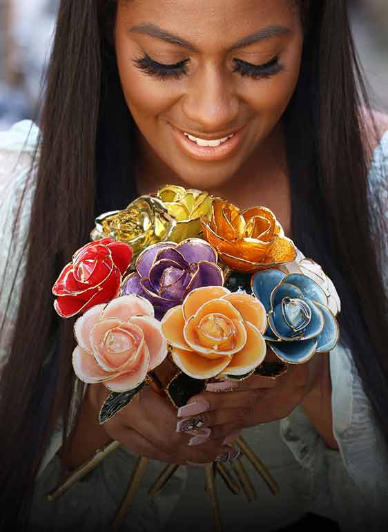 A happy young woman is holding a bouquet of our 24kt yellow gold and rose gold dipped roses