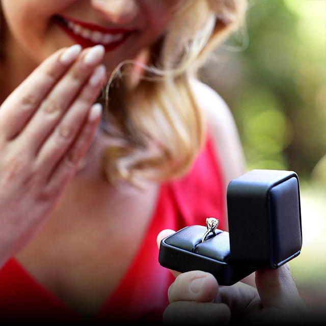 A woman surprised at a proposal receiving our most loved Christa Engagement Ring.