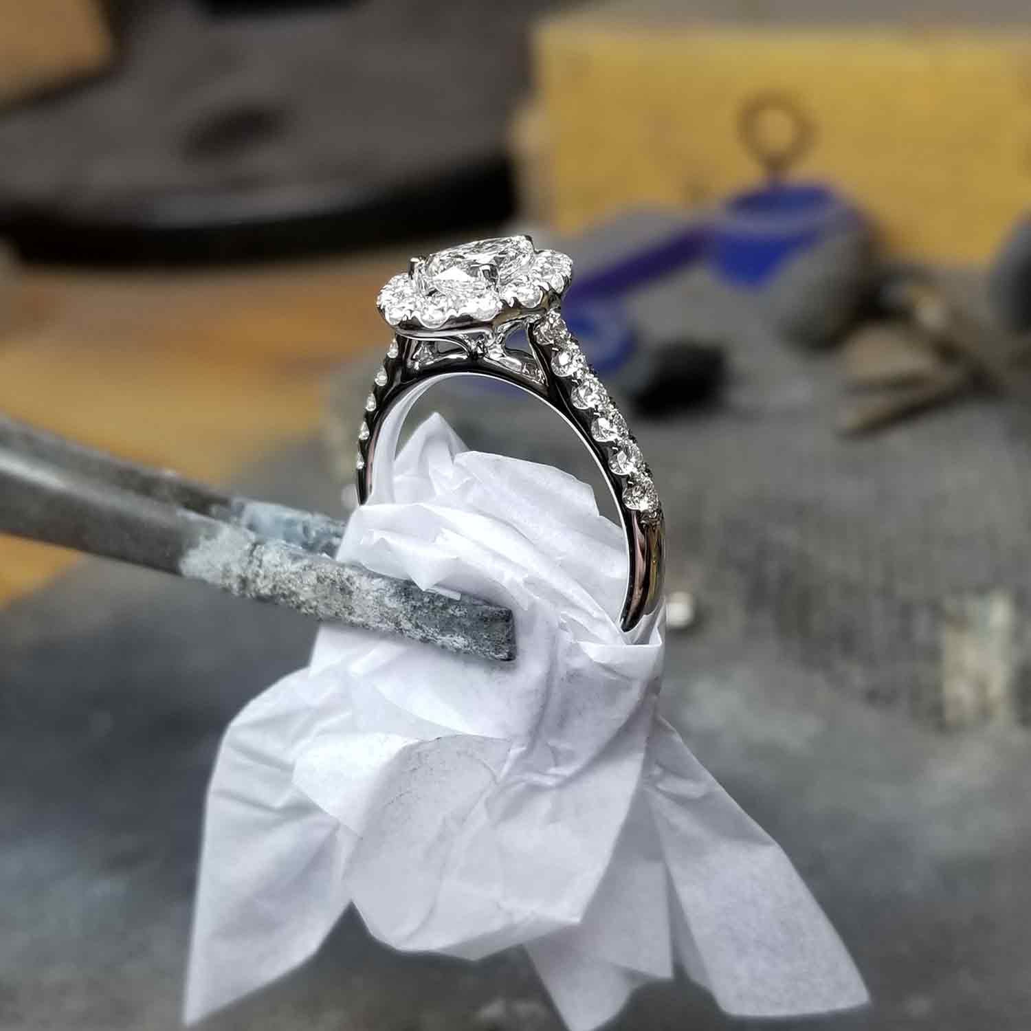 Tweezers holding up a glistening diamond ring.