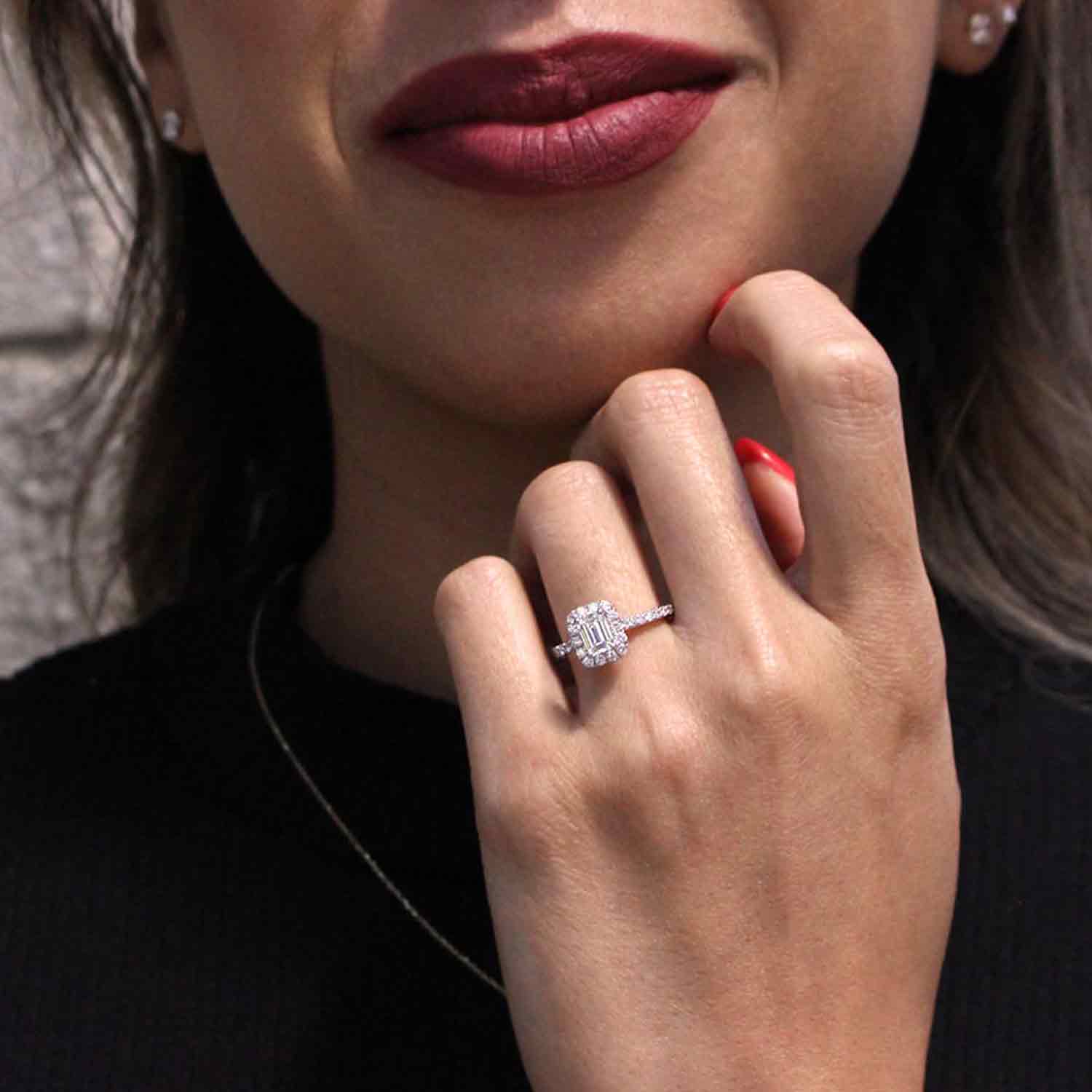 A smiling woman showing off our white gold diamond step cut ring.