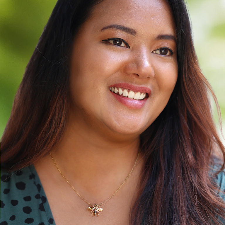 A smiling woman wearing our Honey Love Bee necklace.