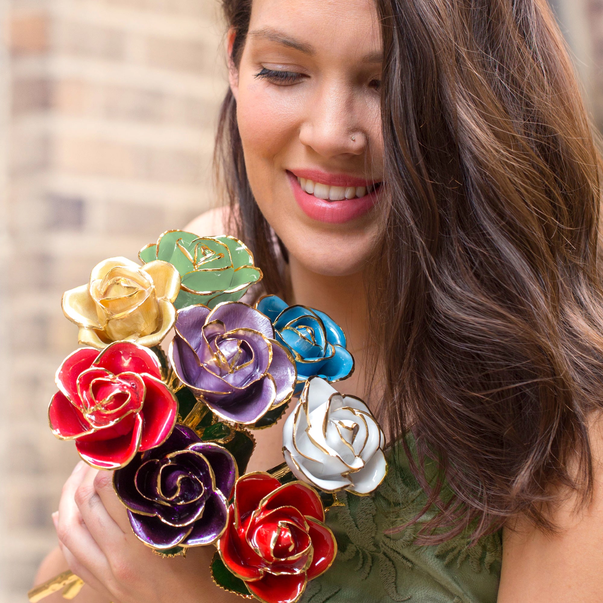 Picture of a woman holding a bouquet of gold dipped roses in various colors. 