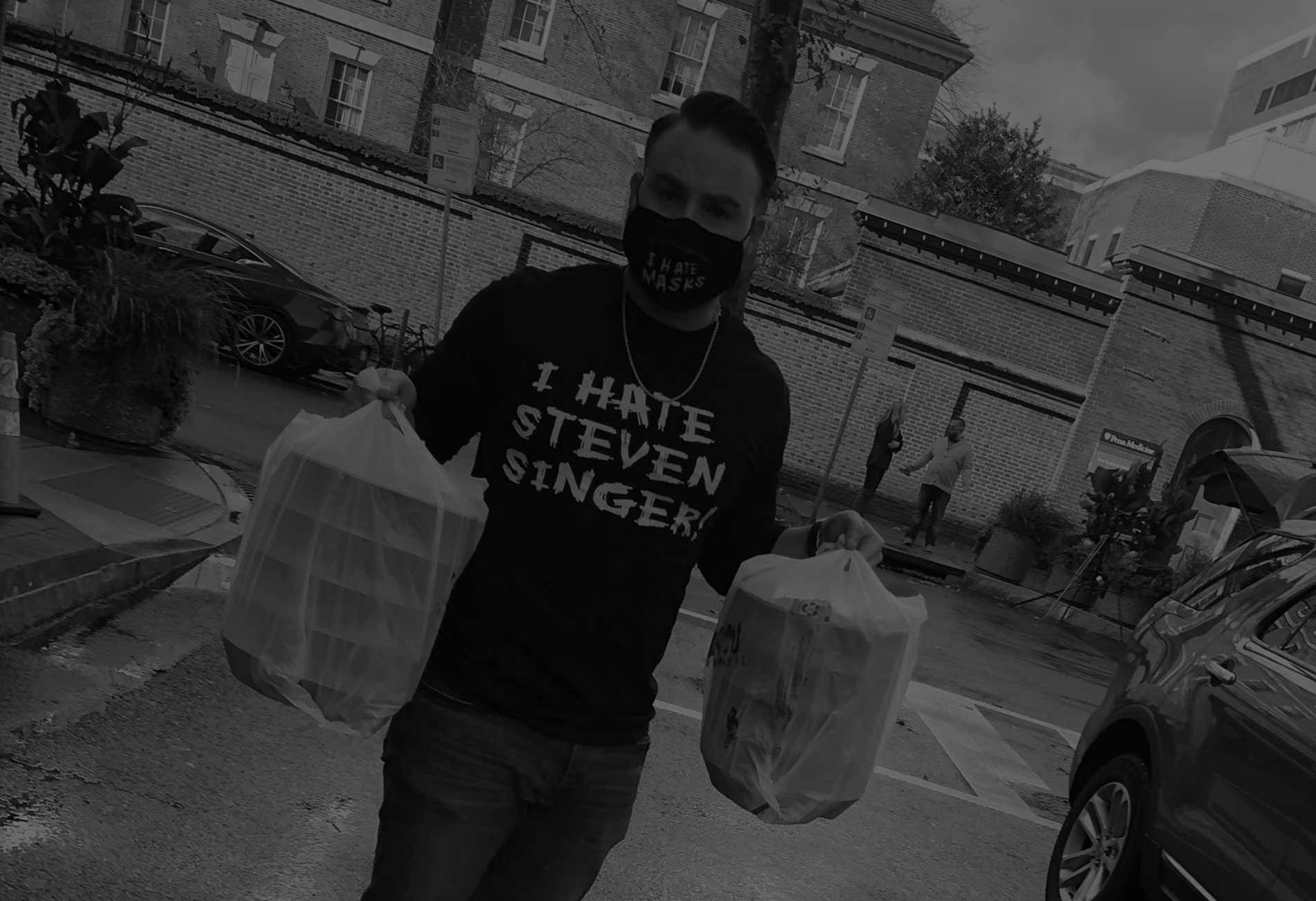 A young man holding up 2 bags of food.