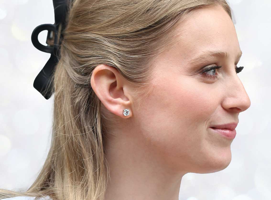 A side profile of a woman smiling with a black bow in her hair wearing our Moonlight Aquamarine Stud Earrings.