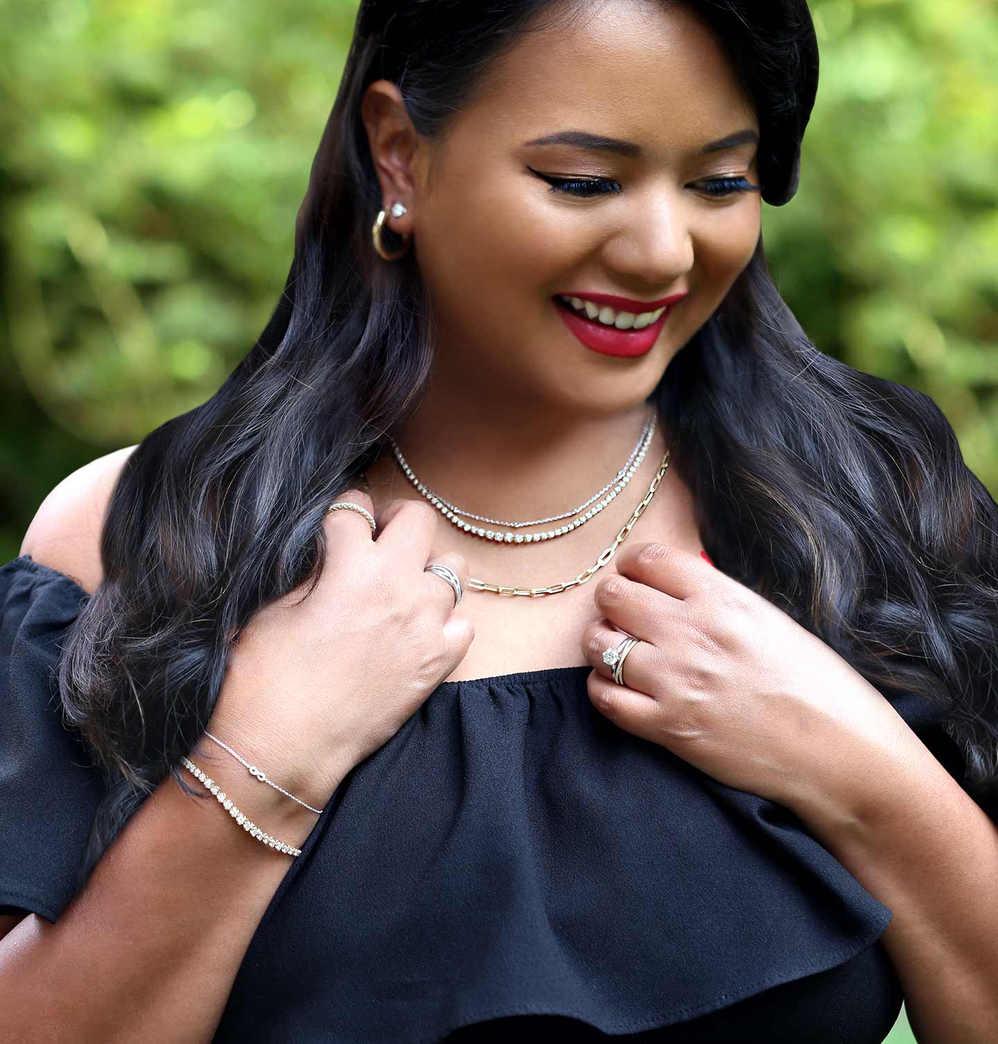 A trendy girl wearing layered necklaces, bracelets, rings, and hoop earrings.