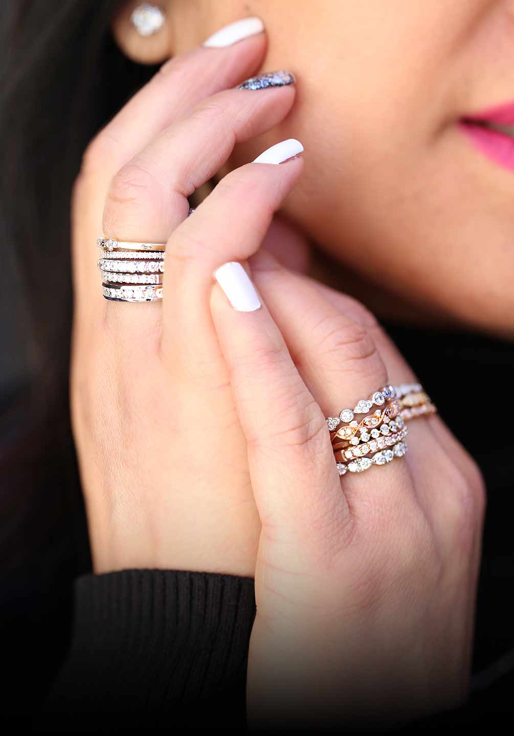 Woman with hands near face wearing stacked up diamond wedding bands in 14 karat white, yellow and rose gold