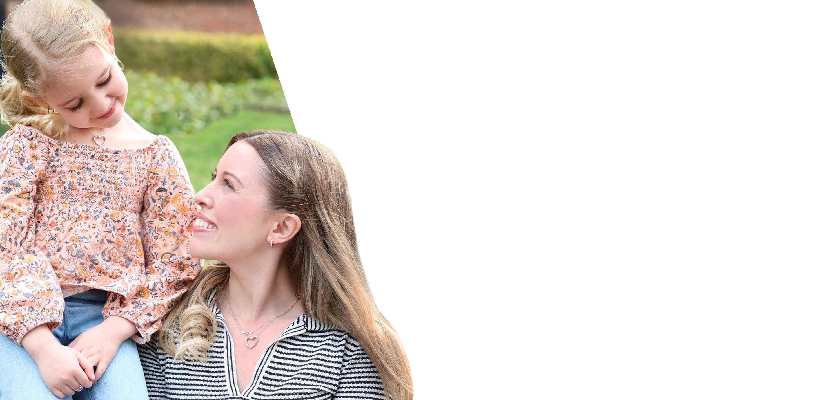 A mother with her daughter sitting together outdoors wearing earrings and necklaces from our Mother's Day Gift Collection 2026.