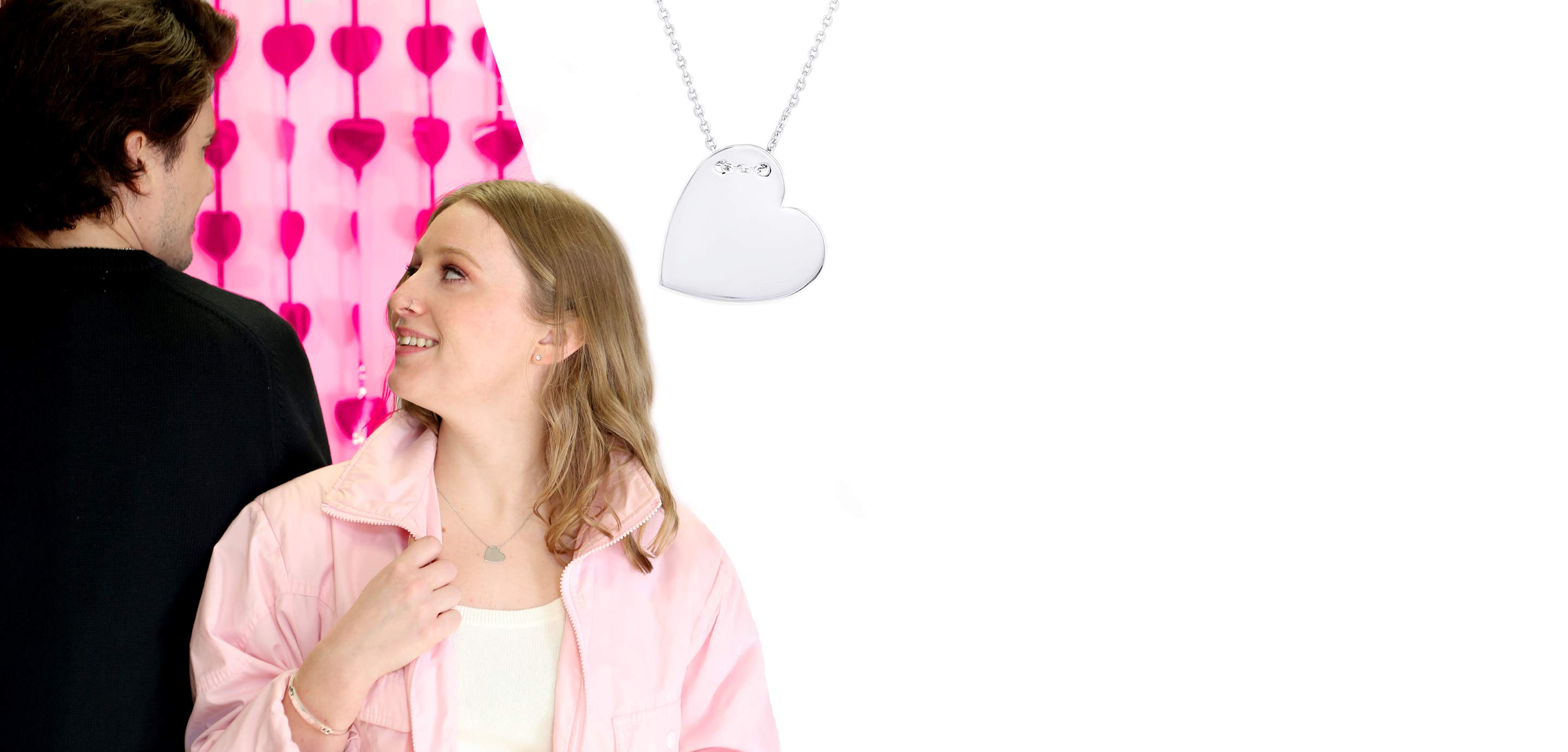 A couple looking in each others eyes and a silver heart necklace.