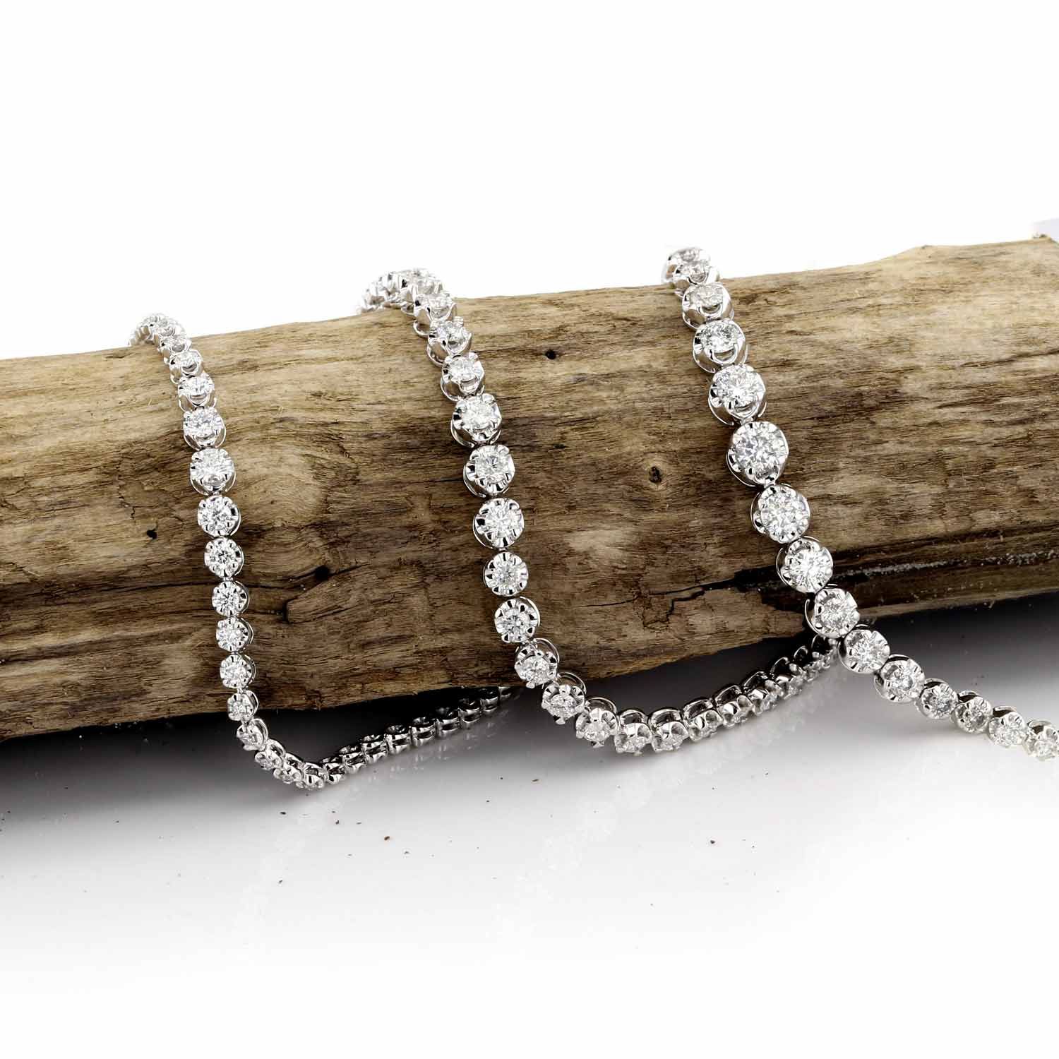 Three mirage style tennis bracelets on a piece of wood. Directs to shop tennis bracelets