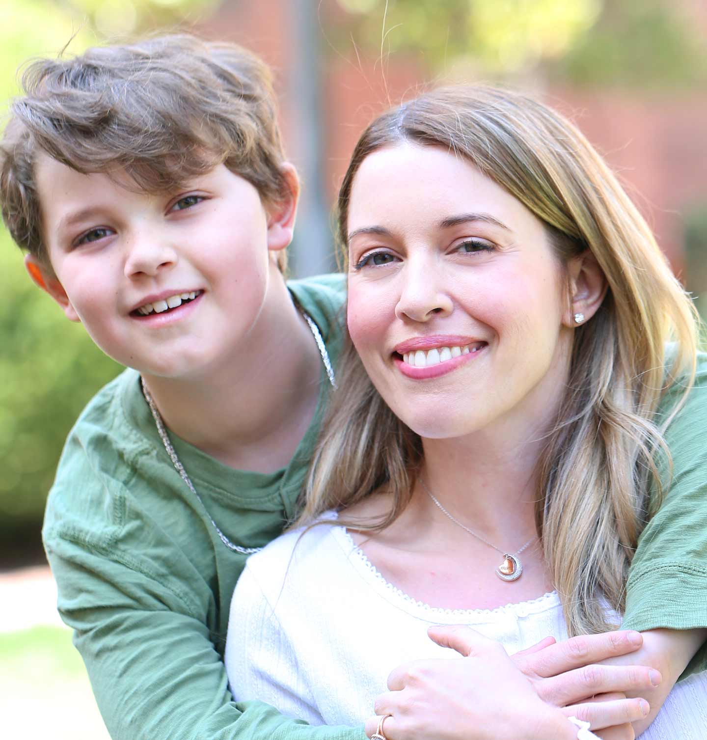A woman and her son hugging each other and smiling.