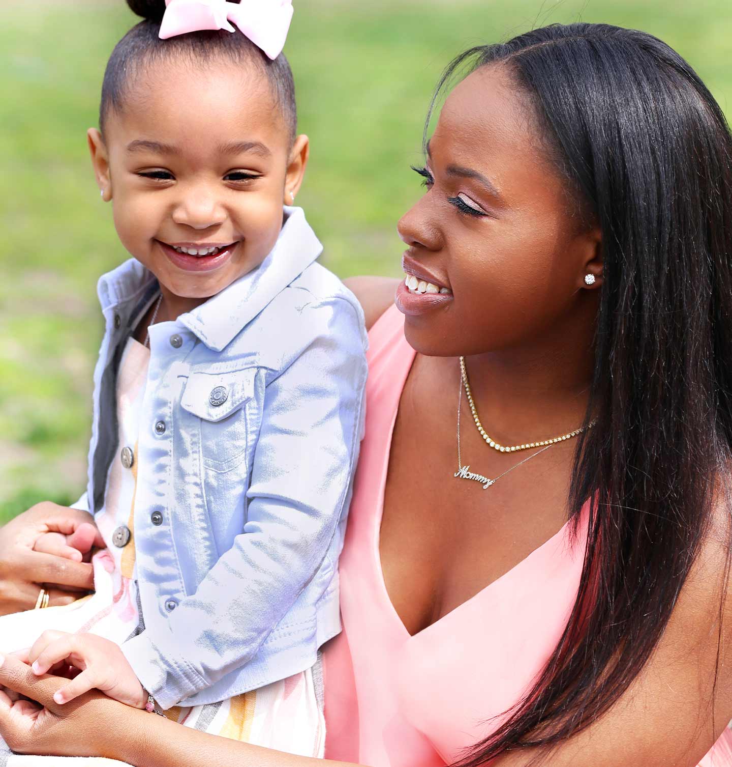 A woman and her daughter sitting together smiling and wearing classic diamond jewelry.