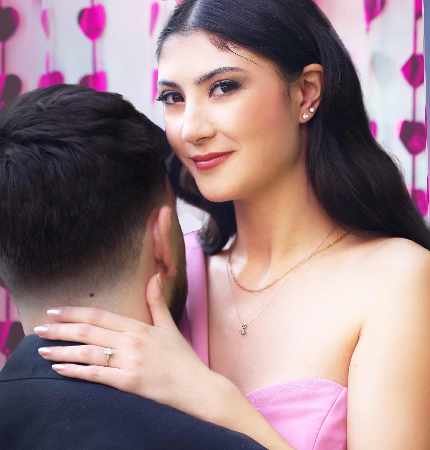 An engaged woman wearing classic diamond studs and a solitaire oval engagement ring.