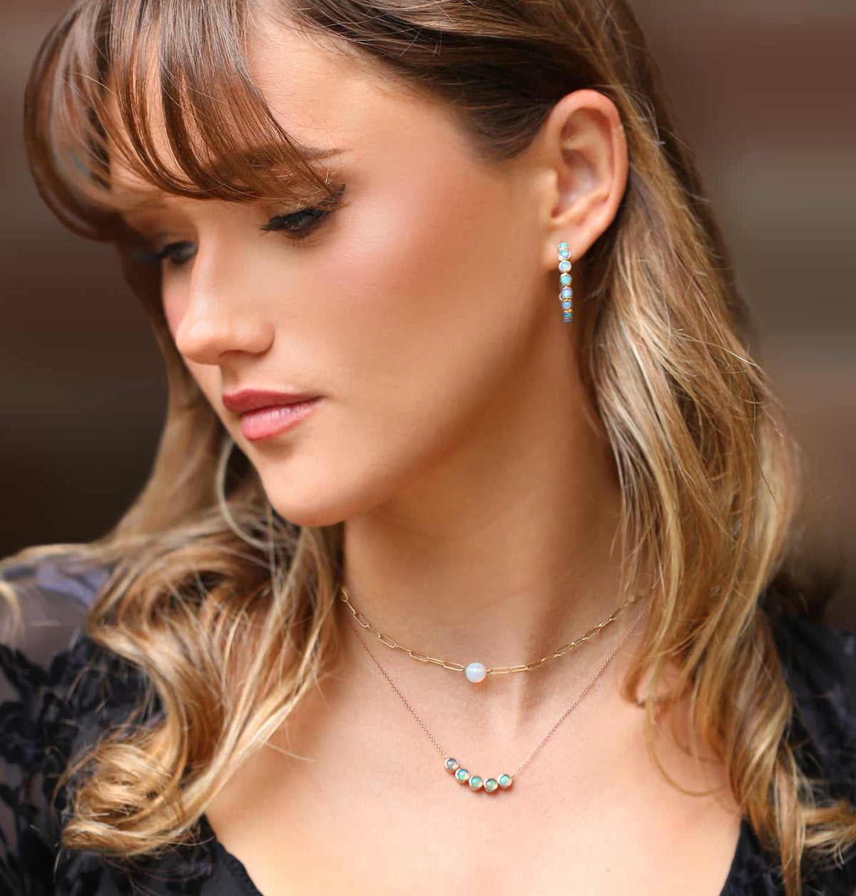 A girl looking down wearing opal jewelry from our October Birthday Collection.