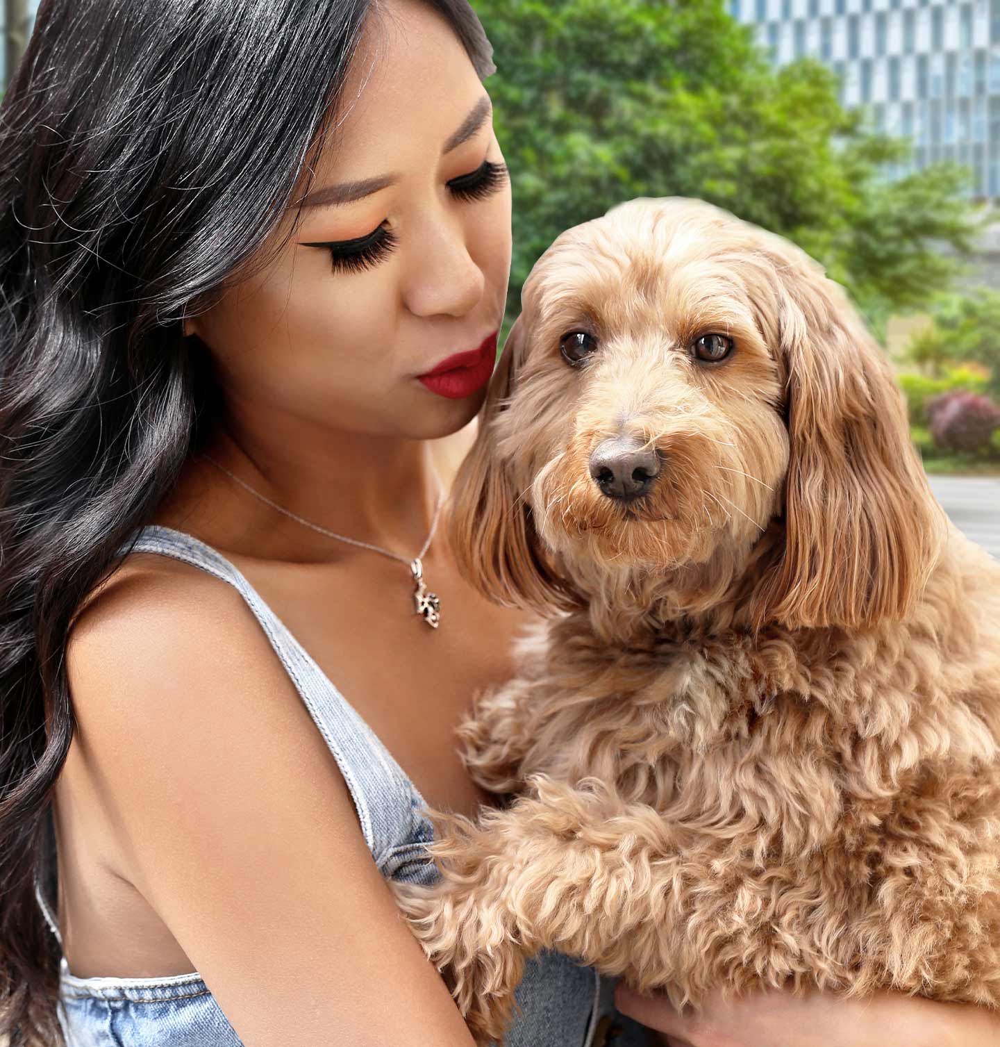 A woman holding a tan dog and wearing a necklace from our Pet Collection.