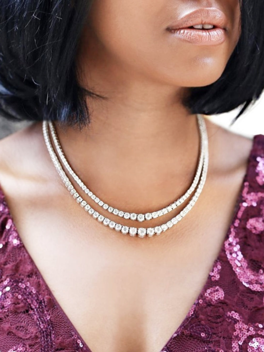 A lady styling two of our tennis necklaces in a layered style 