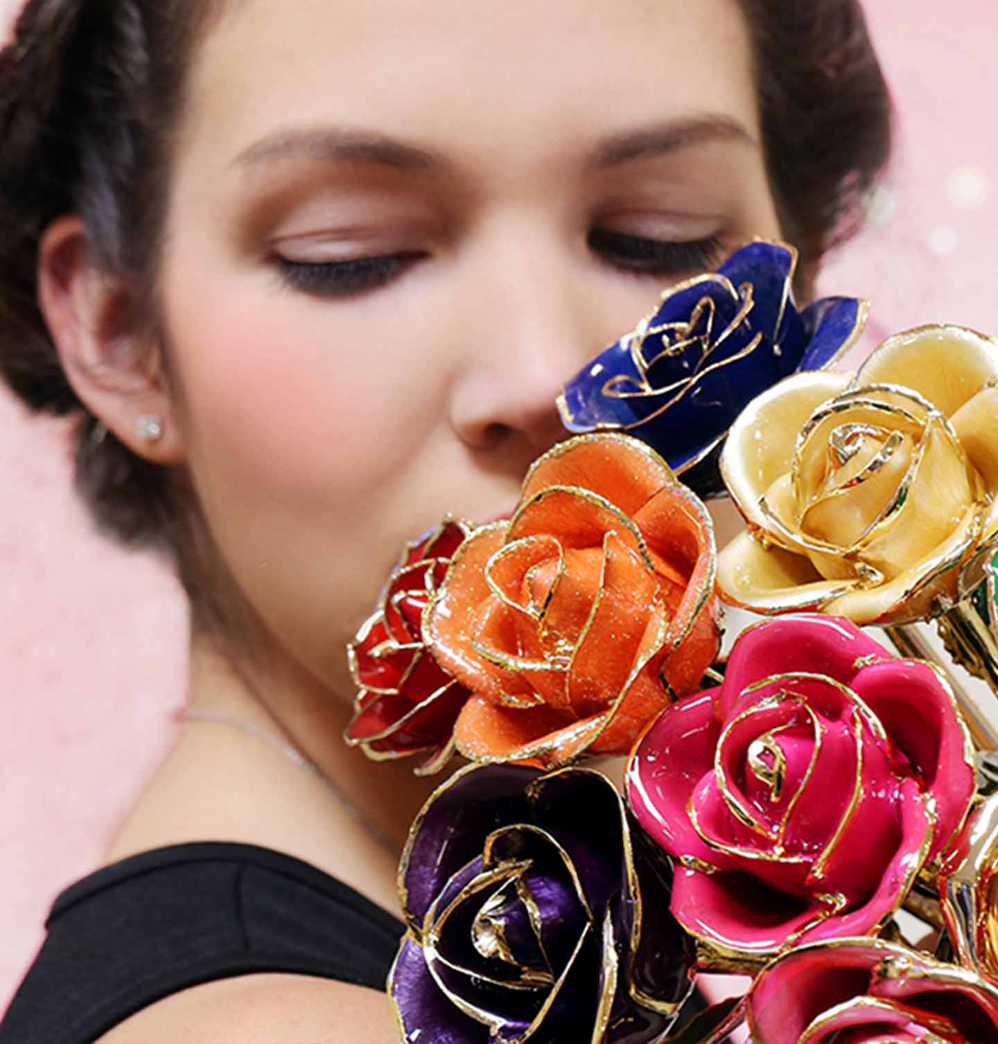A girl looking down holding a bouquet of gold dipped roses in a variety of colors.