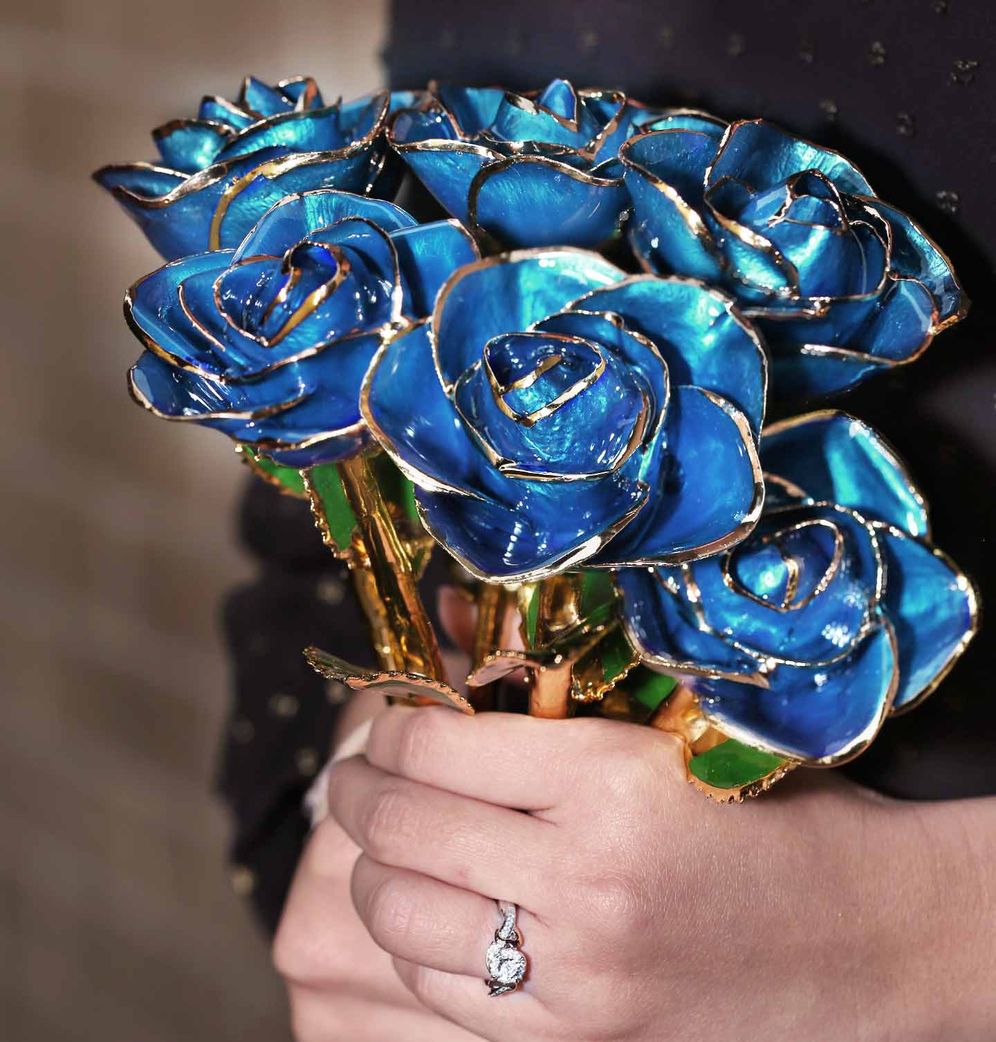 A woman holding a bouquet of Royal Sapphire 24 Karat Gold Dipped Roses.