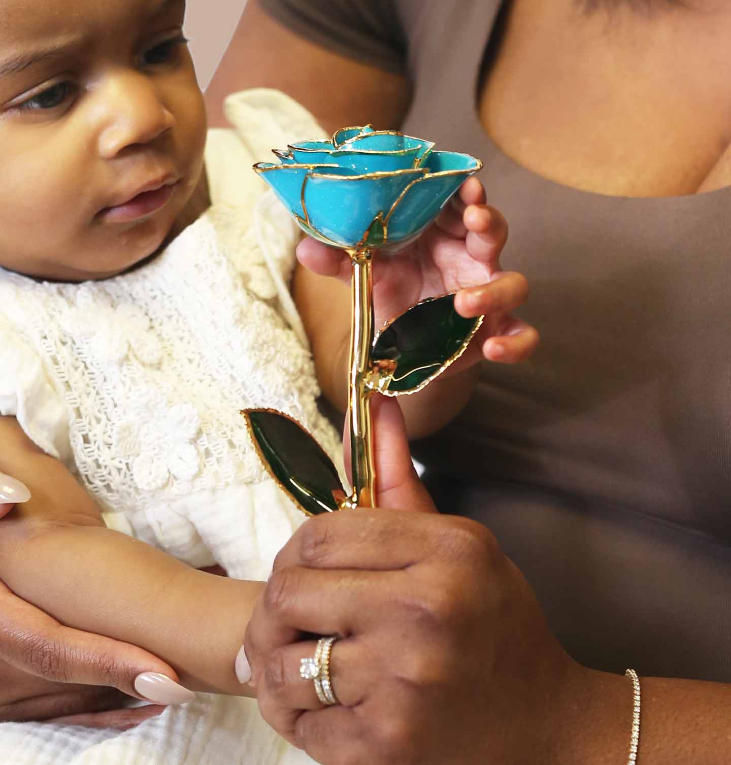 A picture of a mother holding her daughter holding our Blue Moon 24 Karat Gold Dipped Rose.