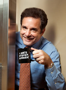 Steve smiling in a dress shirt and tie holding up an "I Hate Steven Singer" mug.