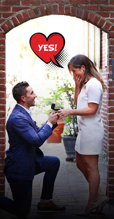 A man proposing to his significant other under a brick archway with a "YES!" word bubble coming from the woman.