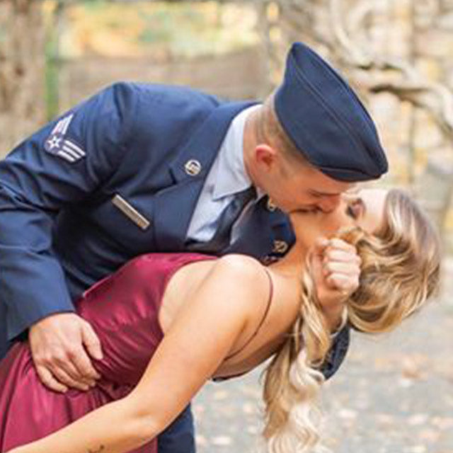 A hard working soldier leaning over and kissing his woman.