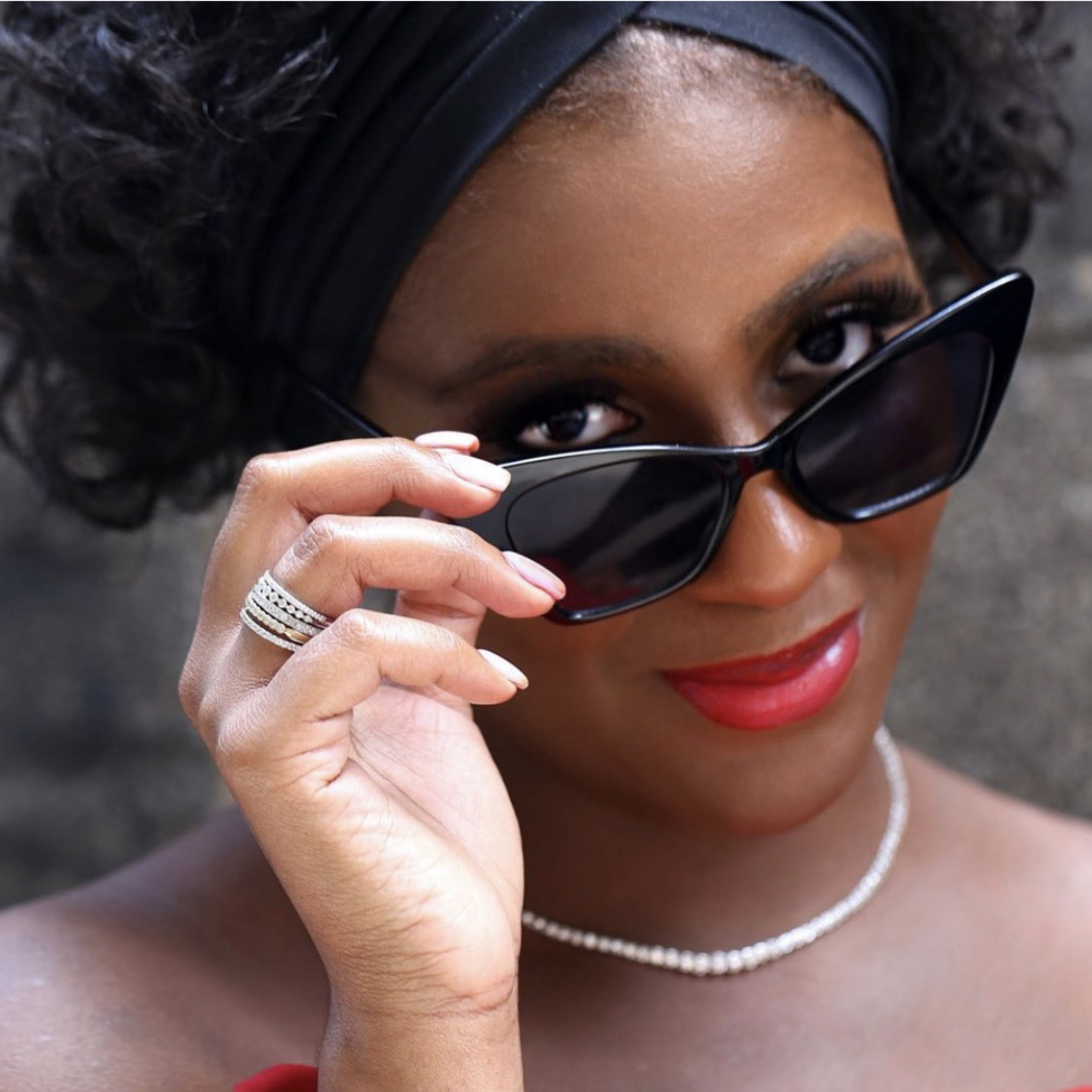 A woman presenting our stackable rings on her right ring finger while holding down the shades from her eyes.