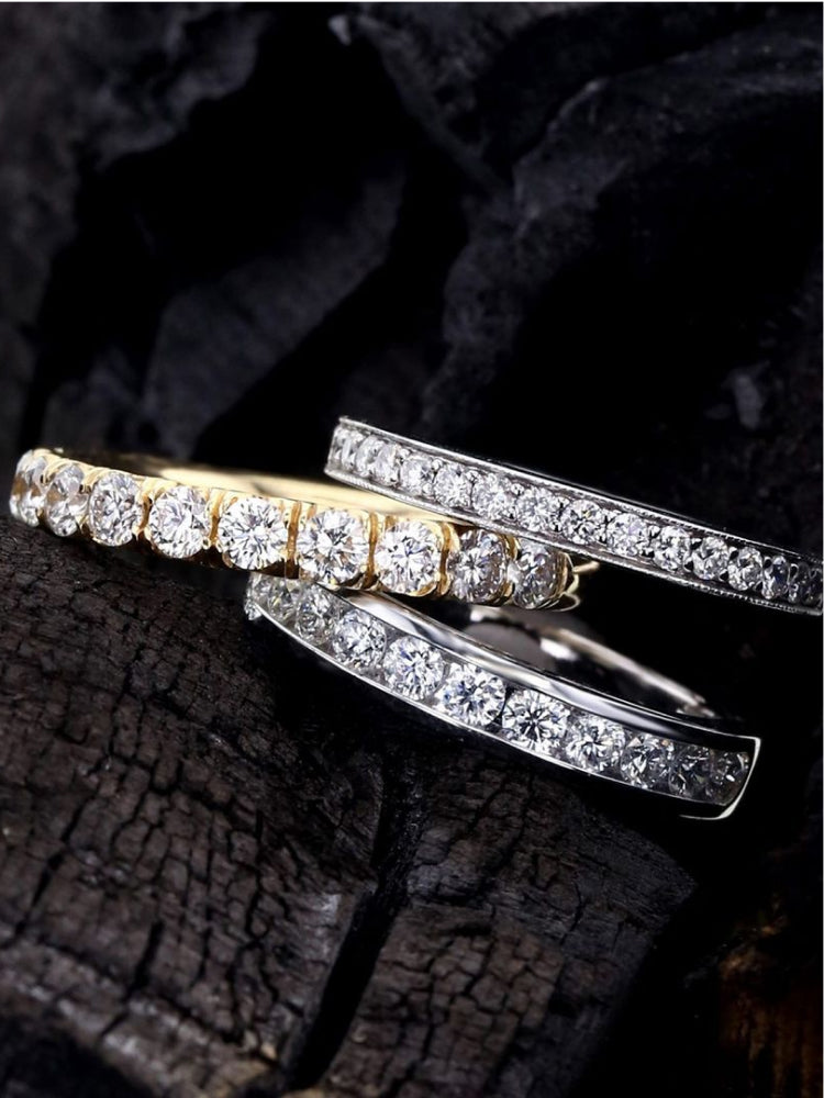 A diamond yellow gold stackable ring in between two diamond white gold stackable rings.