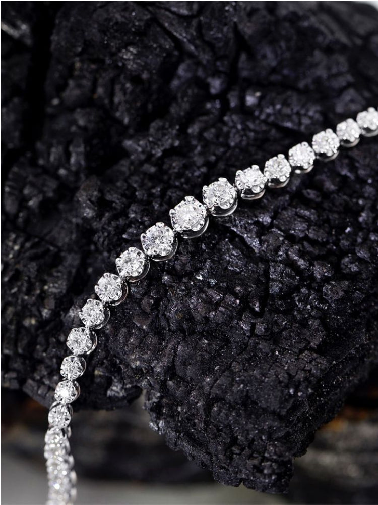 An authentic diamond tennis bracelet on a black rock.